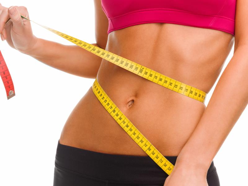 Woman measuring her belly with measuring tape