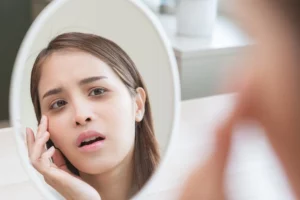woman looking at her under-eye bags in the mirror
